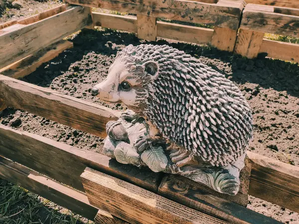 Kirpinin bahçe heykelciği. Kehribar kirpisi bir sehpanın üzerinde. Oyuncak kirpi. Bahçe dekoru. Sokak dekoru. retro biçimi.