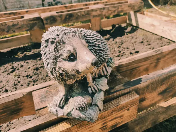 Kirpinin bahçe heykelciği. Kehribar kirpisi bir sehpanın üzerinde. Oyuncak kirpi. Bahçe dekoru. Sokak dekoru. retro biçimi.