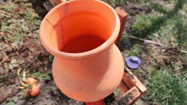 Antika kil sürahi. Ahşap bir çitin üzerindeki kil sürahi bahçedeki bir ağacın arka planına karşı. Kadim büyük kavanoz, içme suyu, su kaynağı, akan su, musluk suyu. Retro biçimi.