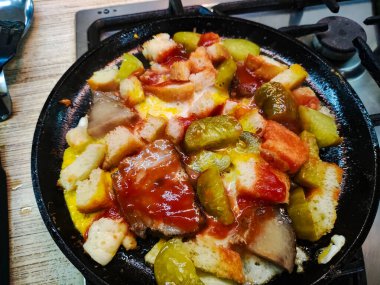 Alışılmadık ev yapımı çırpılmış yumurta. Çırpılmış yumurta, ekmek ve salatalık. Yağda ve yumurta. Kızartma tavasında domuz yağı. Ev yapımı yemek pişirmek. Kızarmış yumurta, doğranmış domates, soğan ve kırmızı biber..