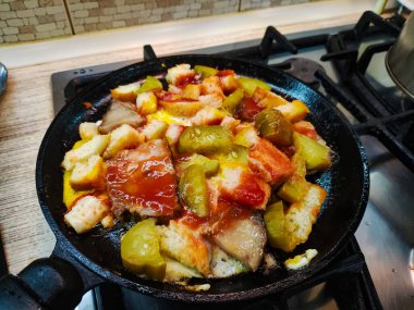 Alışılmadık ev yapımı çırpılmış yumurta. Çırpılmış yumurta, ekmek ve salatalık. Yağda ve yumurta. Kızartma tavasında domuz yağı. Ev yapımı yemek pişirmek. Kızarmış yumurta, doğranmış domates, soğan ve kırmızı biber..