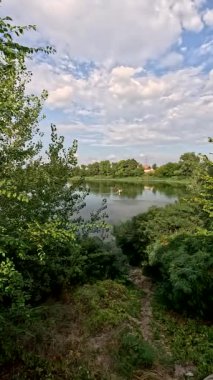 Sonbaharda yol boyunca yürüyorum. Sonbahar manzarası. Sonbahar yaprakları yerde. Dar yol. Nehir kenarında yürüyüş. Göl ve gökyüzü. Güzel doğal manzara. HDR video 4K 60 fps.