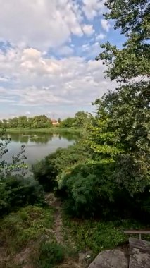 Sonbaharda yol boyunca yürüyorum. Sonbahar manzarası. Sonbahar yaprakları yerde. Dar yol. Nehir kenarında yürüyüş. Göl ve gökyüzü. Güzel doğal manzara. HDR video 4K 60 fps.