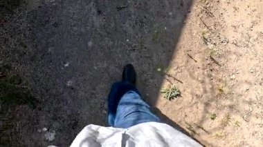 Bir adam kötü bir yolda yürüyor. Bacakları bir patikada yürüyor. Bacakları dolambaçlı bir yolda yürüyor. Bir adam yürüyor.