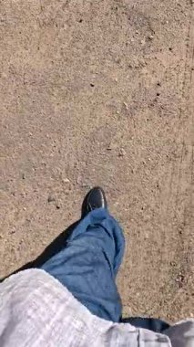 Bir adam kötü bir yolda yürüyor. Bacakları bir patikada yürüyor. Bacakları dolambaçlı bir yolda yürüyor. Bir adam yürüyor.
