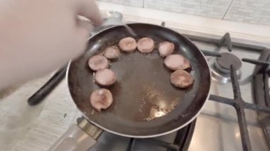 Kızarmış sosisler kızartma tavasında. Kızartma tavasında bir parça sosis. Yağda kızartılmış et. Ev yemeği. Evde yemek pişirmek. Günlük profil videosu. Nötr renkli hdr video. renksiz 4k video.