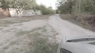 İlk araba kullanan kişi. Taştan arabaya kötü bir yol. Yolda kocaman delikler var. Tehlikeli araba sürme. Araba tekerleği. Günlük profil videosu. Nötr renkli hdr video. renksiz 4k video.