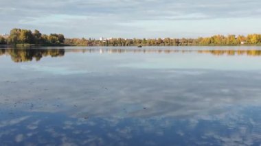 Suyla doğal manzara. Suda yansıması olan güzel bir manzara. Gökyüzü suya yansıyor. Gün batımında nehir. Şafakta göl. Su yüzeyi. Balık tutmak. Göldeki evler.