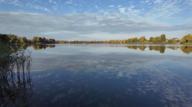 Suyla doğal manzara. Suda yansıması olan güzel bir manzara. Gökyüzü suya yansıyor. Gün batımında nehir. Şafakta göl. Su yüzeyi. Balık tutmak. Göldeki evler.