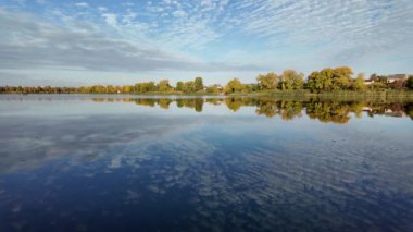 Suyla doğal manzara. Suda yansıması olan güzel bir manzara. Gökyüzü suya yansıyor. Gün batımında nehir. Şafakta göl. Su yüzeyi. Balık tutmak. Göldeki evler.