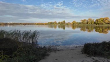 Suyla doğal manzara. Suda yansıması olan güzel bir manzara. Gökyüzü suya yansıyor. Gün batımında nehir. Şafakta göl. Su yüzeyi. Balık tutmak. Göldeki evler.