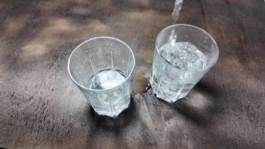 Su şeffaf bir cam yavaş çekim videosunda. Bir bardağa dökülen beyaz şarabın yaratıcı makro yavaş çekim videosu. Soda, yüzen su yüzeyini kapatır. Maden suyu dökülüyor şeffaf