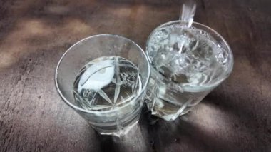 Su şeffaf bir cam yavaş çekim videosunda. Bir bardağa dökülen beyaz şarabın yaratıcı makro yavaş çekim videosu. Soda, yüzen su yüzeyini kapatır. Maden suyu dökülüyor şeffaf