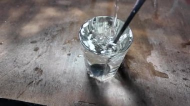 Su şeffaf bir cam yavaş çekim videosunda. Bir bardağa dökülen beyaz şarabın yaratıcı makro yavaş çekim videosu. Soda, yüzen su yüzeyini kapatır. Maden suyu dökülüyor şeffaf