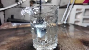 Su şeffaf bir cam yavaş çekim videosunda. Bir bardağa dökülen beyaz şarabın yaratıcı makro yavaş çekim videosu. Soda, yüzen su yüzeyini kapatır. Maden suyu dökülüyor şeffaf