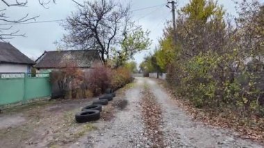 Köy yolu. Gri Cinder Yolu. Lastikten yapılmış çiçek yatakları. Yolun kenarındaki lastikler. taşra köyü.