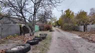 Köy yolu. Gri Cinder Yolu. Lastikten yapılmış çiçek yatakları. Yolun kenarındaki lastikler. taşra köyü.