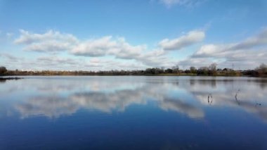 Suda yansıması olan muhteşem bir manzara. Bulutlar ve ağaçlar suya yansıyor. Güzel göl. Temiz nehir. Doğal manzara. Günlük profili. Düz renk profili. Sahilde gün doğumu ve gün batımı.