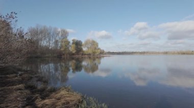 Suda yansıması olan muhteşem bir manzara. Bulutlar ve ağaçlar suya yansıyor. Güzel göl. Temiz nehir. Doğal manzara. Günlük profili. Düz renk profili. Sahilde gün doğumu ve gün batımı.