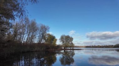 Suda yansıması olan muhteşem bir manzara. Bulutlar ve ağaçlar suya yansıyor. Güzel göl. Temiz nehir. Doğal manzara. Günlük profili. Düz renk profili. Sahilde gün doğumu ve gün batımı.