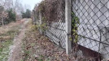 Ağdan yapılmış demir çitler. Demir ve beton çitler. Eski bir çit boyunca yürüyen bir adam.