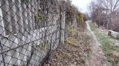 Ağdan yapılmış demir çitler. Demir ve beton çitler. Eski bir çit boyunca yürüyen bir adam.