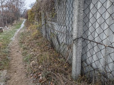 Ağdan yapılmış demir çitler. Demir ve beton çitler. Eski bir çit boyunca yürüyen bir adam.