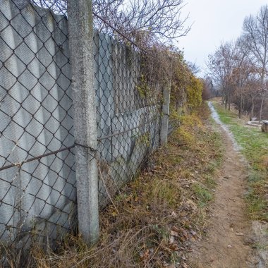 Ağdan yapılmış demir çitler. Demir ve beton çitler. Eski bir çit boyunca yürüyen bir adam.