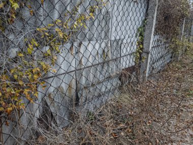 Ağdan yapılmış demir çitler. Demir ve beton çitler. Eski bir çit boyunca yürüyen bir adam.
