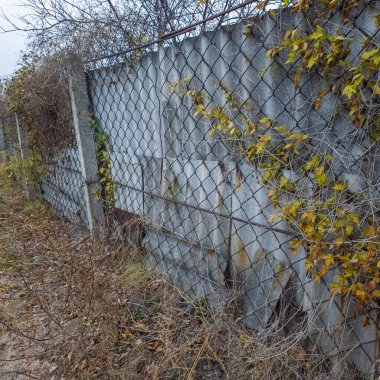 Ağdan yapılmış demir çitler. Demir ve beton çitler. Eski bir çit boyunca yürüyen bir adam.