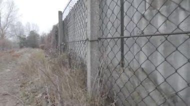 Ağdan yapılmış demir çitler. Demir ve beton çitler. Eski bir çit boyunca yürüyen bir adam.