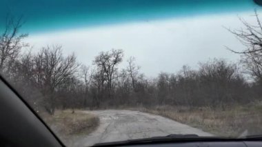 Sürücü yavaş çekimde bir video kullanıyor. Araba kullanan ilk kişi sensin. Kötü gri hava ve kötü yol. Asfalttaki çukurlar.