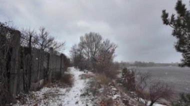 Kışın doğa yürüyüşü. Kar yağıyormuş. Yavaş çekim videosu. Karlı bir yol. Kışın yürü. Karda eski demir çitler.