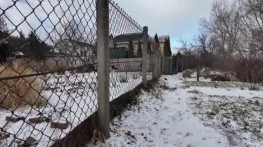 Kışın doğa yürüyüşü. Kar yağıyormuş. Yavaş çekim videosu. Karlı bir yol. Kışın yürü. Karda eski demir çitler.