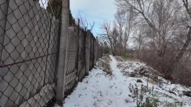 Kışın doğa yürüyüşü. Kar yağıyormuş. Yavaş çekim videosu. Karlı bir yol. Kışın yürü. Karda eski demir çitler.