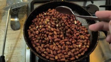 Kızarmış fıstık. Adam kızartma tavasında fıstık kızartıyor..