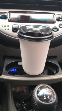 Arabada bir fincan cappuccino. Arabadaki kahve. Sürücü elinde bir içki tutuyor. Arabada bir bardak tutacağı. Şoförün elinde latte. Kâğıt kahve fincanı adamın elinde. Araba yola park edilmiş, gezginin sıcak kahvesi.