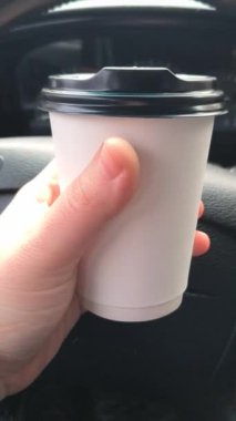 Arabada bir fincan cappuccino. Arabadaki kahve. Sürücü elinde bir içki tutuyor. Arabada bir bardak tutacağı. Şoförün elinde latte. Kâğıt kahve fincanı adamın elinde. Araba yola park edilmiş, gezginin sıcak kahvesi.