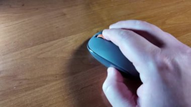 Adam bir bilgisayar faresi tutuyor. El ele tutuşup bir bilgisayar faresini beyaz arka planda hareket ettiriyoruz. Çalışma masasındaki siyah bilgisayar faresi. Bir PC ile çalışmak ve fareye tıklamak.