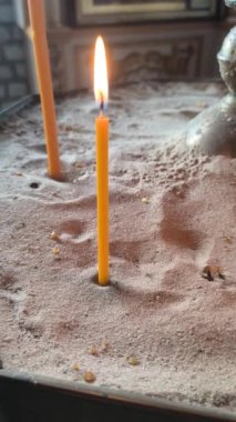 Bir şamdanda yanan dikey video mumları. dini mumlar. Sarı kilise mumları kumda yanıyor.