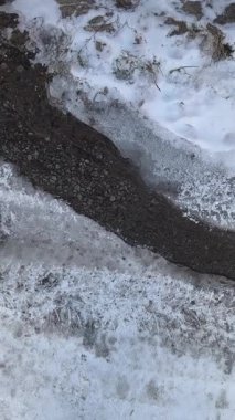 Yoldaki dikey buz videosu. Donmuş yol. Kalın buzlar yolda eriyor..