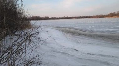 Nehirdeki buz. İlkbaharda buz yavaşça nehirde yüzüyor. Yüzen donmuş buz blokları olan nehir. Kıyıdaki karlar ve ağaçlar donuyor. Nehirdeki buz. Donmuş nehirde yürü. 4k video
