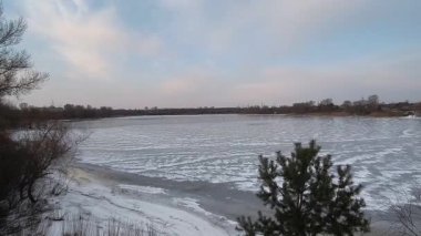 Nehirdeki buz. İlkbaharda buz yavaşça nehirde yüzüyor. Yüzen donmuş buz blokları olan nehir. Kıyıdaki karlar ve ağaçlar donuyor. Nehirdeki buz. Donmuş nehirde yürü. 4k video