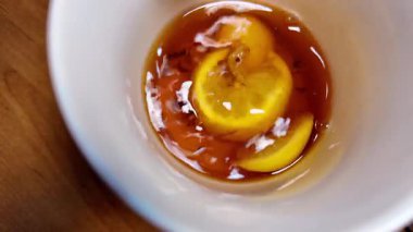 Siyah çay ve limon yavaş çekim videosu. Bardakta çay. bir fincan çayın içinde yüzen limon.