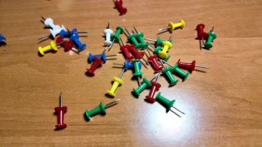 Ağır çekim videosundaki iğneleri itin. Masaya renkli raptiyeler düşüyor. Dünya 'nın ya da şehrin haritasını işaretlemek için iğne çiziyorum. Plastik raptiyeler. Yakın çekim..