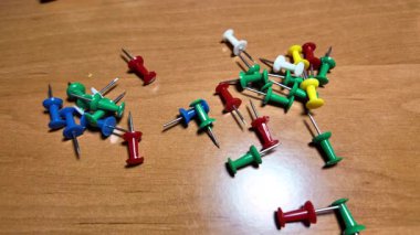 Ağır çekim videosundaki iğneleri itin. Masaya renkli raptiyeler düşüyor. Dünya 'nın ya da şehrin haritasını işaretlemek için iğne çiziyorum. Plastik raptiyeler. Yakın çekim..