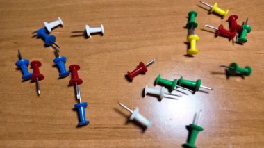 Ağır çekim videosundaki iğneleri itin. Masaya renkli raptiyeler düşüyor. Dünya 'nın ya da şehrin haritasını işaretlemek için iğne çiziyorum. Plastik raptiyeler. Yakın çekim..