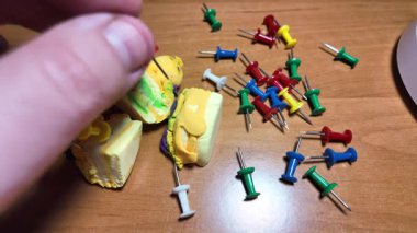 Ağır çekim videosundaki iğneleri itin. Masaya renkli raptiyeler düşüyor. Dünya 'nın ya da şehrin haritasını işaretlemek için iğne çiziyorum. Plastik raptiyeler. Yakın çekim..