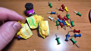 Ağır çekim videosundaki iğneleri itin. Masaya renkli raptiyeler düşüyor. Dünya 'nın ya da şehrin haritasını işaretlemek için iğne çiziyorum. Plastik raptiyeler. Yakın çekim..