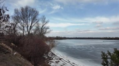 Donmuş göl üzerindeki ağır çekim kış manzarası. Nehirde buzlar kırıldı. Vahşi doğada kuş gözlemciliği. 4K 'de ağır çekim videosu. Göl kıyısının soğuk kış soğuğunun elde tutulan videosu.